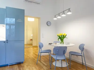 a dining room with a table and blue chairs at Tyzenhauz Suites Topolowa in Kraków