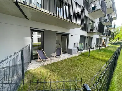 a yard with two chairs and a fence in front of a building at Apartment Barrier-Free in Kraków