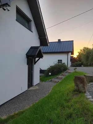 a white house with a black roof and a yard at Domki Na Wiosce in Stryszowa