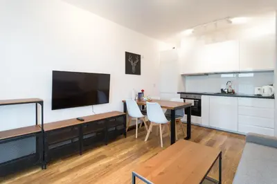 a living room with a kitchen and a table with chairs at Zabłocie Comfort Suite in Kraków