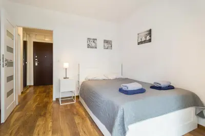 a white bedroom with a bed with blue towels on it at Zabłocie Comfort Suite in Kraków