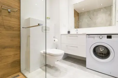 a bathroom with a toilet and a washing machine at Zabłocie Comfort Suite in Kraków