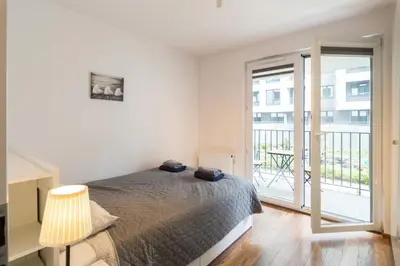 a white bedroom with a bed and a balcony at Zabłocie Comfort Suite in Kraków