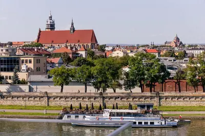 a couple of boats in the water near a city at Nadwiślańska11 - Klimatyczny apartament tuż nad Wisłą in Kraków