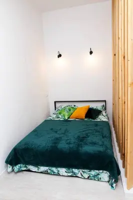 a bed with a green comforter in a bedroom at Apartment Quiet Street 11/2E in Oświęcim