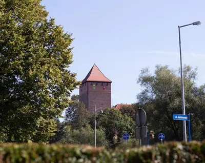 a building with a tower in the distance with trees at Apartment Quiet Street 11/2E in Oświęcim