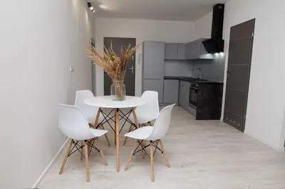 a dining room with a white table and white chairs at Apartment Quiet Street 11/2E in Oświęcim