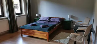 a bedroom with a bed with two chairs and two windows at Dom Gościnny Zawoja in Zawoja