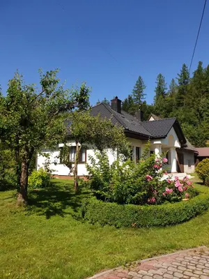 a white house with flowers in the yard at Dom Gościnny Zawoja in Zawoja