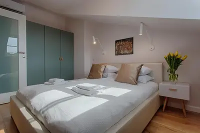 a bedroom with a large white bed with green cabinets at Tyzenhauz Apartments Dietla Street in Kraków