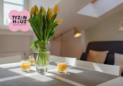 a vase with flowers and glasses on a table at Tyzenhauz Apartments Dietla Street in Kraków