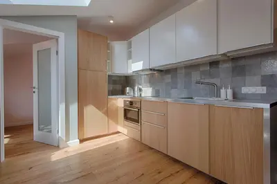 a kitchen with white cabinets and a wooden floor at Tyzenhauz Apartments Dietla Street in Kraków