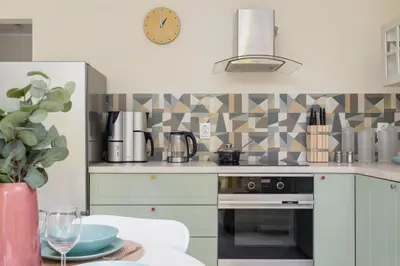a kitchen with a stove and a clock on the wall at Mondrian Cracow - 2 Bedroom Apartment for Home Office by Noclegi Renters in Kraków