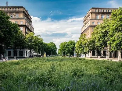 a large field of grass in front of two buildings at Nowa Huta Super Star in Kraków