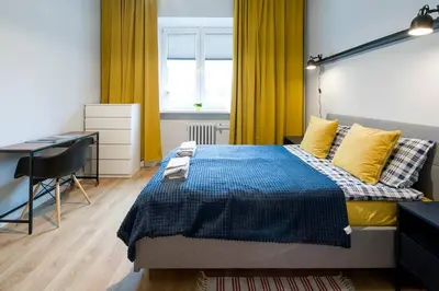 a bedroom with a bed with a desk and yellow curtains at Nowa Huta Super Star in Kraków