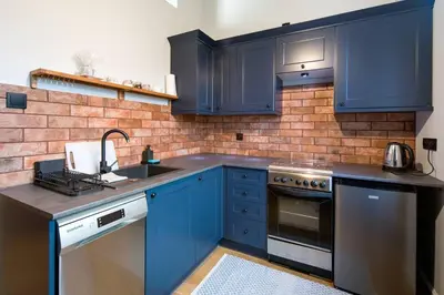 a kitchen with blue cabinets and a brick wall at Nowa Huta Super Star in Kraków