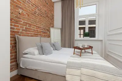 a bedroom with a white bed with a brick wall at Apartment Strzelecka Old Town Cracow by Renters Prestige in Kraków