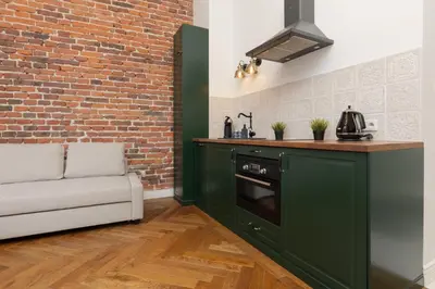 a green kitchen with a couch next to a brick wall at Apartment Strzelecka Old Town Cracow by Renters Prestige in Kraków