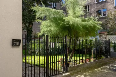 a black fence with a small tree behind it at The Historic Kazimierz District - Apartments with parking by Noclegi Renters in Kraków