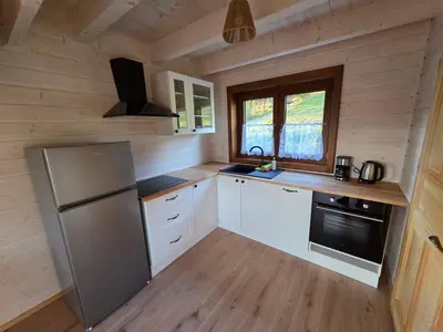 a kitchen with white cabinets and a refrigerator at Blisko natury - chatki z sauną w Zawoi in Zawoja