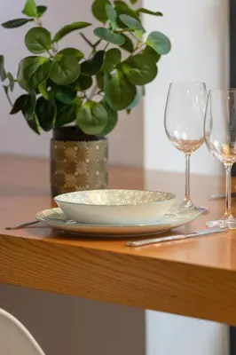 a table with a plate and two wine glasses at Solna Cracow Air-conditioned Apartment with Balcony by Noclegi Renters in Kraków