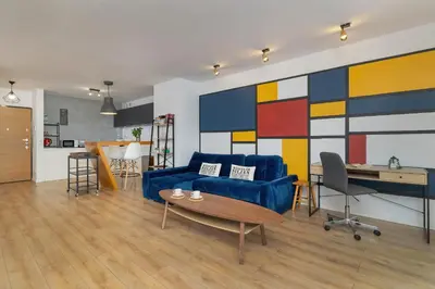 a living room with a blue couch and a colorful wall at Solna Cracow Air-conditioned Apartment with Balcony by Noclegi Renters in Kraków