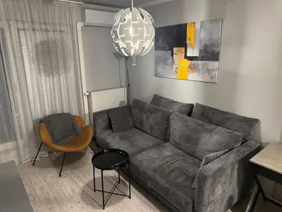 a living room with a gray couch and a chandelier at Modern Apartament (10 min walk to Kazimierz) in Kraków