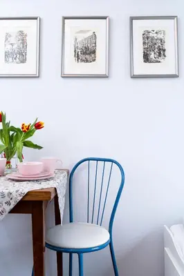 a dining room table with a blue chair and framed pictures at Cozy Old Town Studio in Kraków