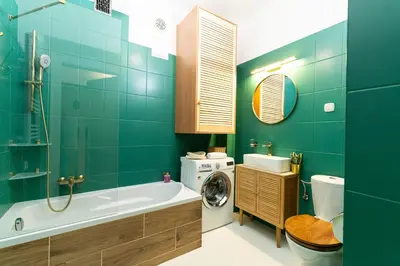 a bathroom with a tub and a washing machine at Cozy Old Town Studio in Kraków