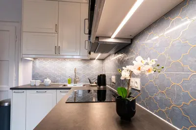 a kitchen with white cabinets and a vase with flowers on the counter at Cozy Old Town Studio in Kraków