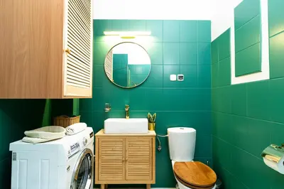 a green bathroom with a washing machine and a sink at Cozy Old Town Studio in Kraków