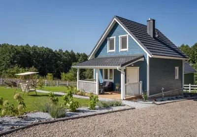 a blue house with a porch and a yard at Staymoovers - ManiaLand Domki pod Krakowem in Paszkówka