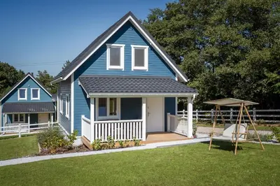 a blue house with a porch and a swing at Staymoovers - ManiaLand Domki pod Krakowem in Paszkówka