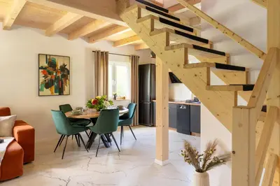 a dining room and living room with a wooden staircase at Staymoovers - ManiaLand Domki pod Krakowem in Paszkówka