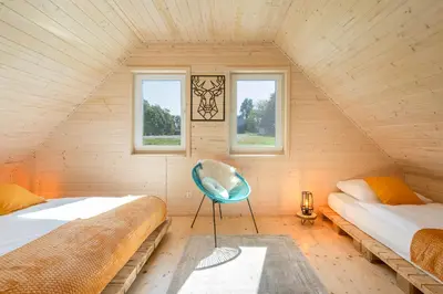 a attic bedroom with two beds and a blue chair at Staymoovers - ManiaLand Domki pod Krakowem in Paszkówka