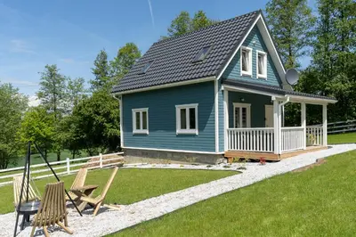 a blue house with a porch and a swing at Staymoovers - ManiaLand Domki pod Krakowem in Paszkówka