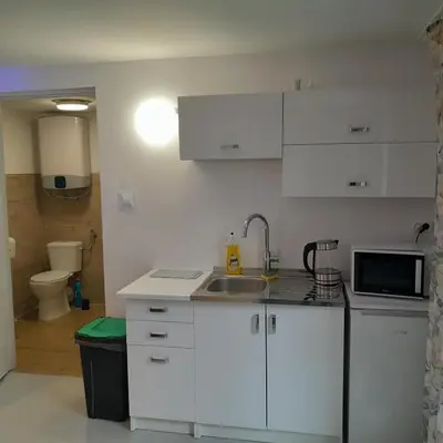 a white kitchen with a sink and a microwave at Domek Muchorek 1km od Energylandii in Zator