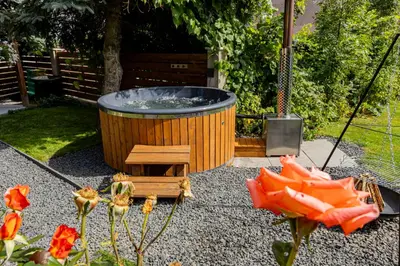 a large hot tub in a garden with flowers at Dom w górach z kominkiem i balią ogrodową Sielanka in Skomielna Czarna