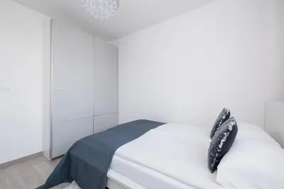 a bedroom with a white bed with black objects on it at Cracow Prądnik Spacious & Family Apartment with 3 bedroom by Renters Prestige in Kraków