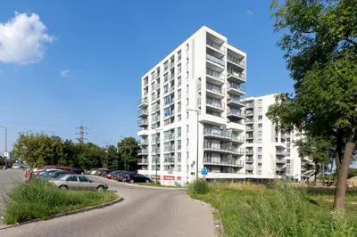 a white apartment building with cars parked in a parking lot at Cracow Prądnik Spacious & Family Apartment with 3 bedroom by Renters Prestige in Kraków