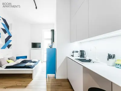 a kitchen with white cabinets and a blue refrigerator at Boom Apartments in Kraków