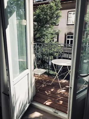 an open door to a balcony with a table and chair at Boom Apartments in Kraków