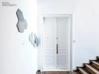 a white door in a white room with stairs at Boom Apartments in Kraków