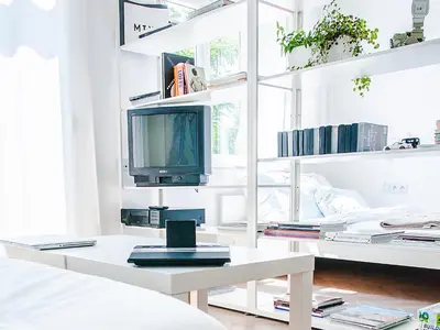a white living room with a tv and a table at Boom Apartments in Kraków