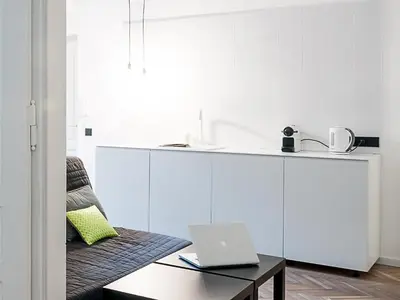 a white kitchen with a laptop on a table at Boom Apartments in Kraków