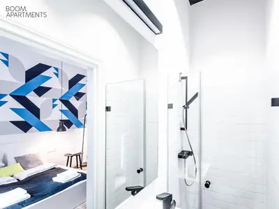 a white bathroom with a shower and a bed at Boom Apartments in Kraków