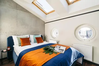 a bedroom with a bed with an orange and blue blanket at Estery12 in Kraków