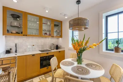 a kitchen with yellow cabinets and a table with chairs at Lisie Sprawki in Bebło