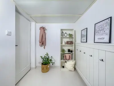 a white hallway with white cabinets and a plant at Apartament przy Rynku Długa 23 in Kraków