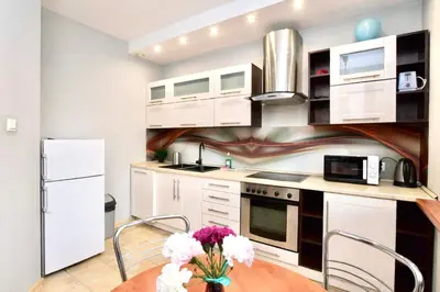 a kitchen with white cabinets and a table with flowers at Rodzinny apartament dla sześciu osób z parkingiem prywatnym in Kraków